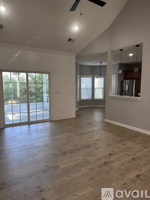A spacious room with wooden flooring and a ceiling fan.