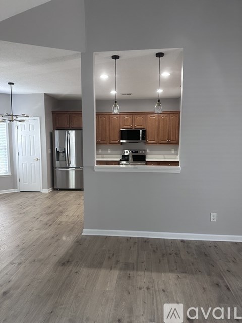 A kitchen with wooden cabinets and a stainless steel refrigerator.