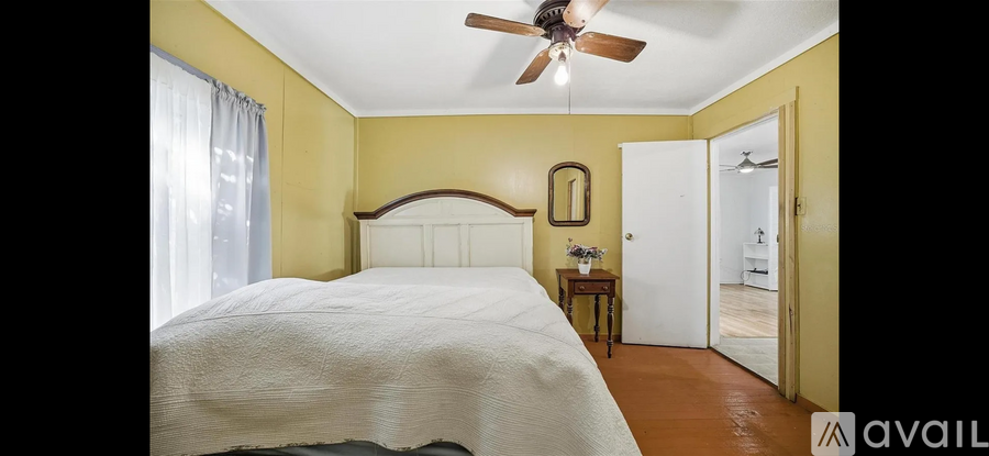 A bedroom with a bed, a ceiling fan, and a mirror.