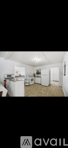A kitchen with white appliances and a dining table.