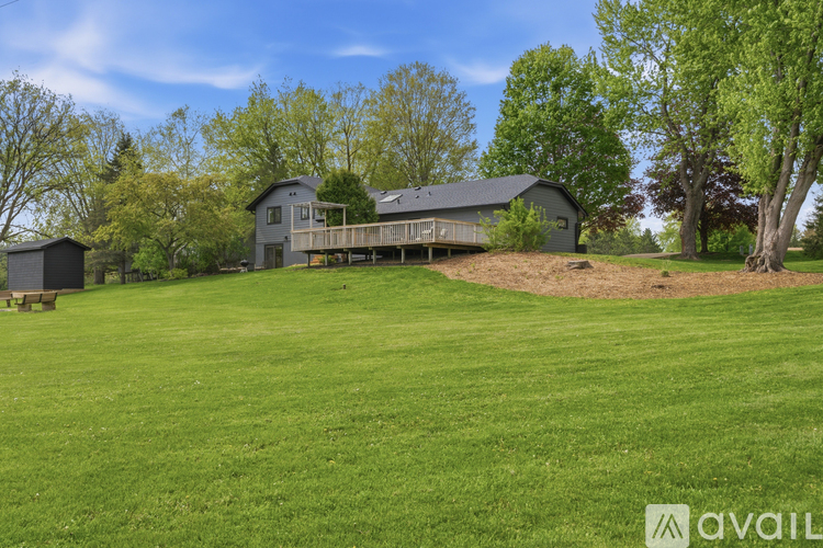 A large grassy field with a house and trees in the background.