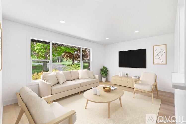 A living room with a white couch, a wooden chair, a coffee table, and a flat screen TV mounted on the wall.
