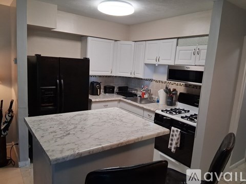 A kitchen with a marble countertop and black appliances.