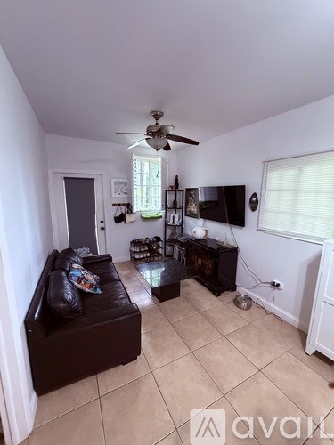 A living room with a black couch and a ceiling fan.