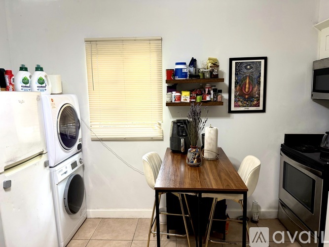 A kitchen with a white fridge, a wooden table with chairs, and a microwave.