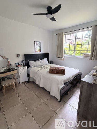 A bedroom with a bed, nightstand, and window.