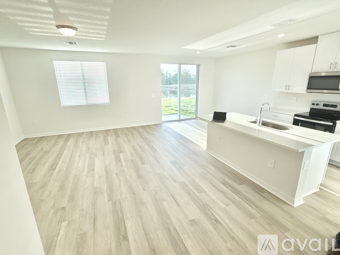 A spacious kitchen with white cabinets and a wooden floor.