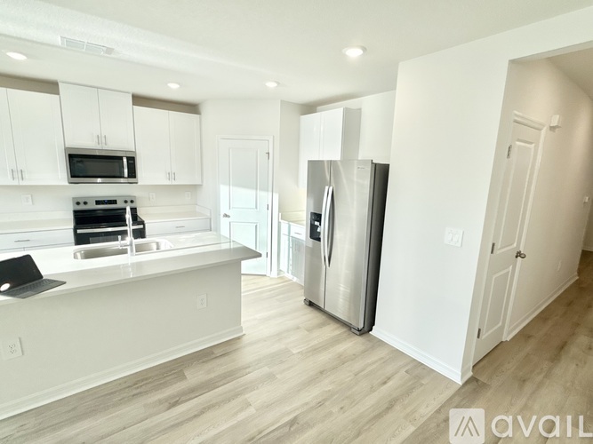 A kitchen with white cabinets and a stainless steel refrigerator.