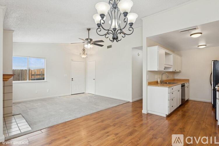 A well-lit, spacious kitchen and living room with hardwood floors and white cabinetry.