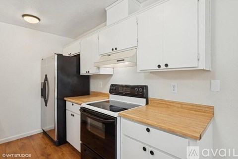 A kitchen with white cabinets and a black refrigerator.