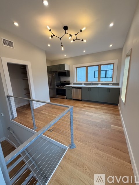 A modern kitchen with wooden floors and a staircase.