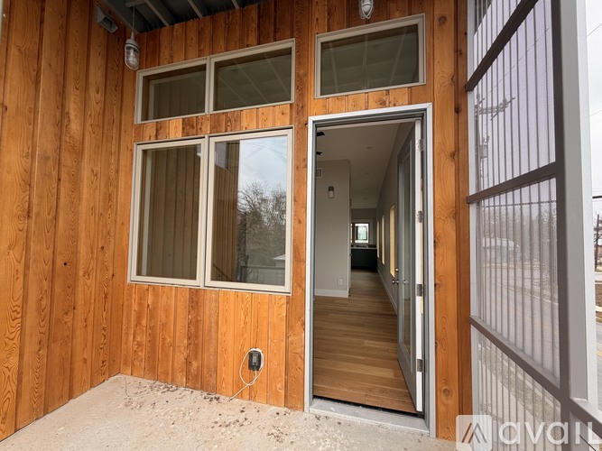 A wooden house under construction with a door open to the interior.
