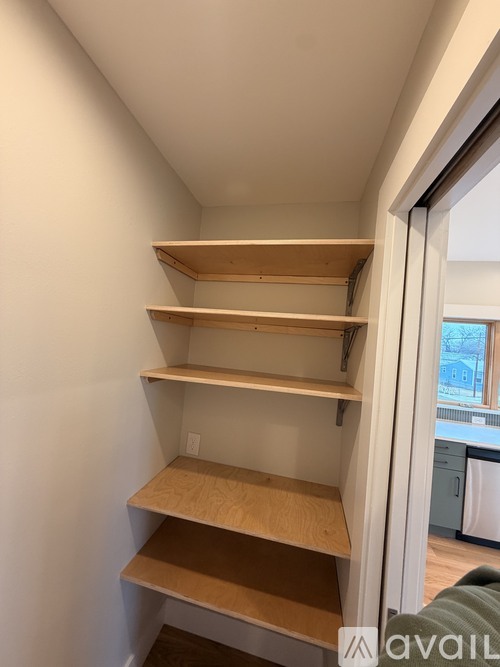 A set of four wooden shelves in a corner of a room.