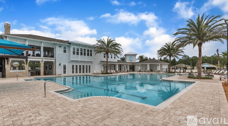 A large outdoor swimming pool surrounded by a tiled patio and palm trees.