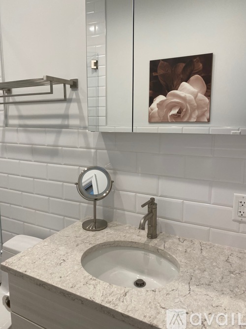 A bathroom with a marble sink and a round mirror.