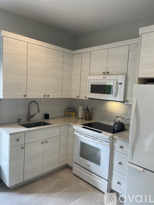 A kitchen with white cabinets and appliances.