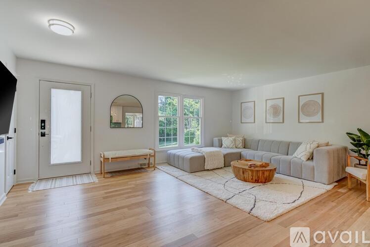 A living room with a grey couch, a wooden coffee table, and a white rug.