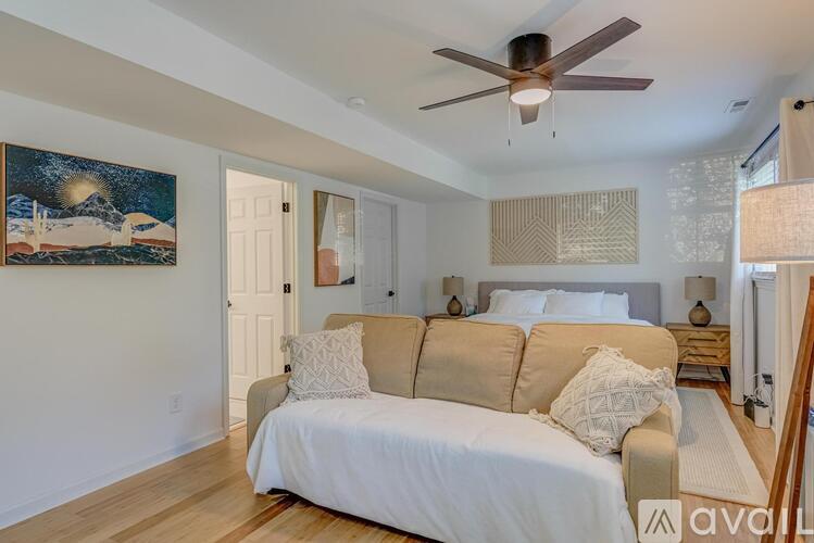 A bedroom with a bed, a couch, and a painting on the wall.