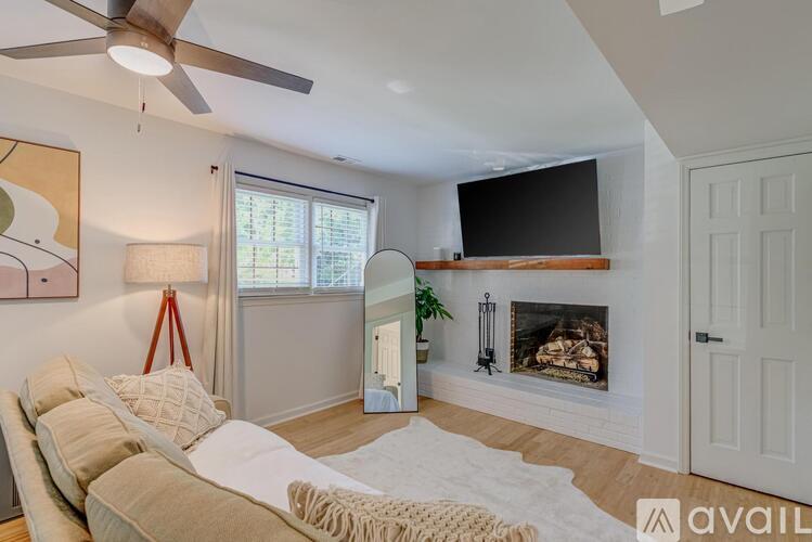 A living room with a fireplace and a television mounted above it.