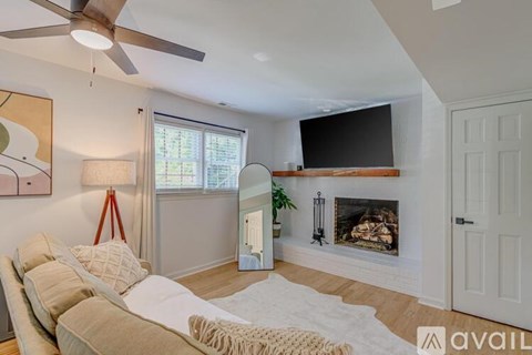 A living room with a fireplace and a television mounted above it.