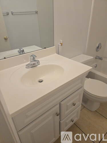 A white bathroom with a sink, toilet and mirror.