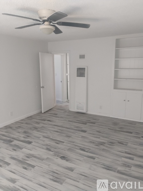 A room with a ceiling fan and a doorway leading to another room.