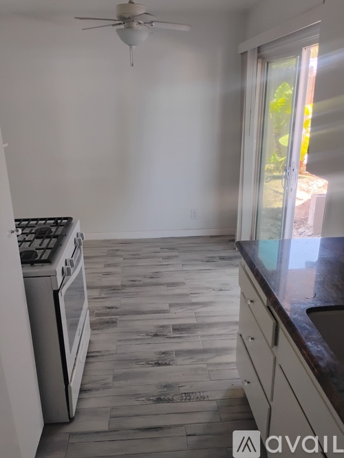 A kitchen with a stove top oven and a fan ceiling.