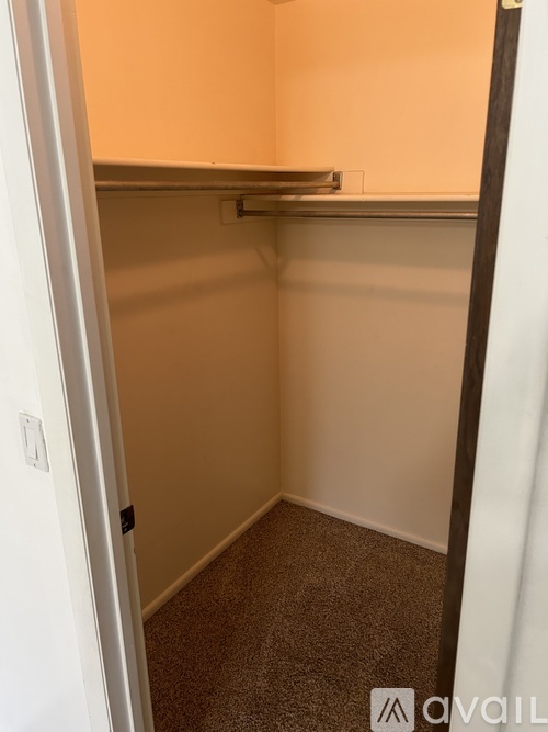 A small, empty room with a carpeted floor and a white door.