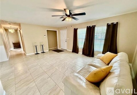 A living room with a white couch and a ceiling fan.