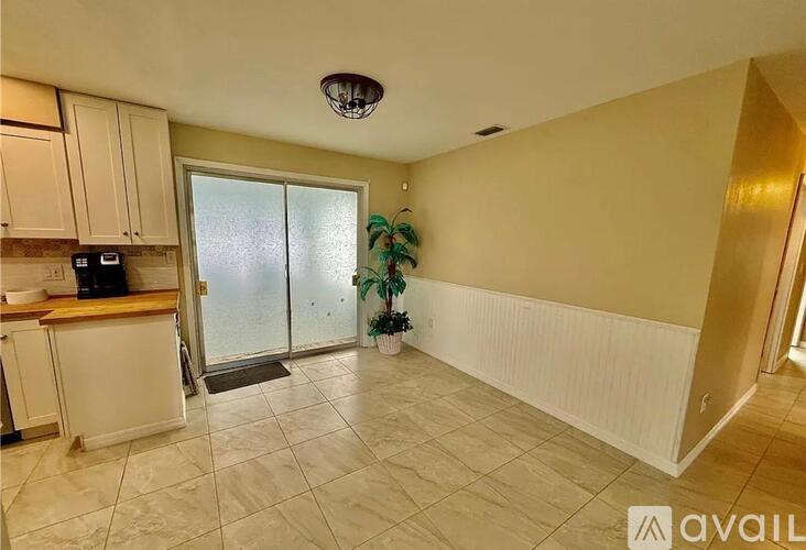 A kitchen area with a tiled floor and a ceiling light fixture.