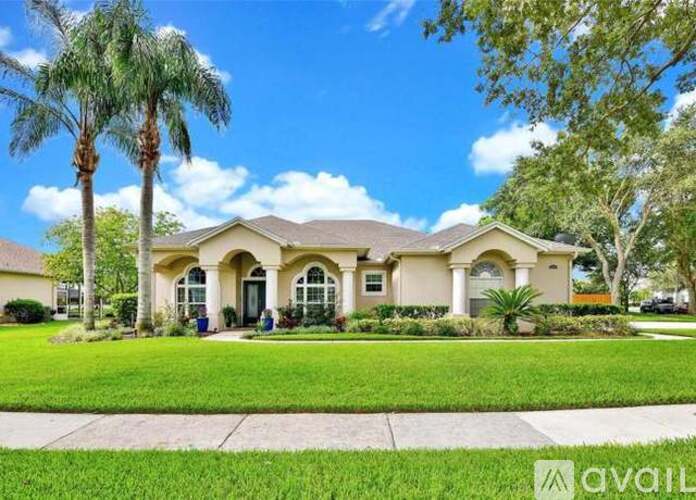 A house with a front yard and palm trees.