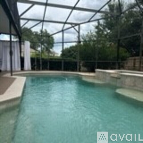 A pool inside a glass house with trees in the background.