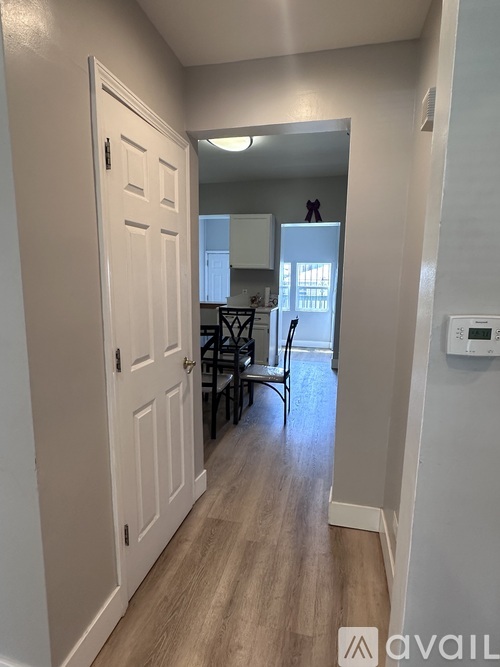 A hallway with a white door and a chair in front of a dining table.