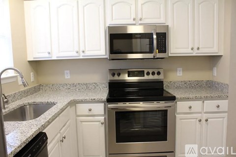 A kitchen with white cabinets and a granite countertop.