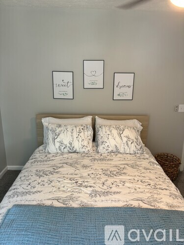 A bedroom with a bed, two pillows, and three framed pictures on the wall.