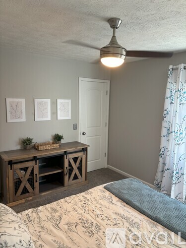 A bedroom with a bed, a table, and a ceiling fan.