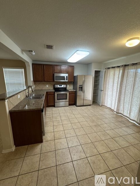 A kitchen with brown cabinets and a tiled floor.