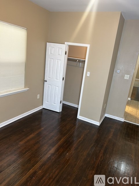 A room with a white door and wooden floors.