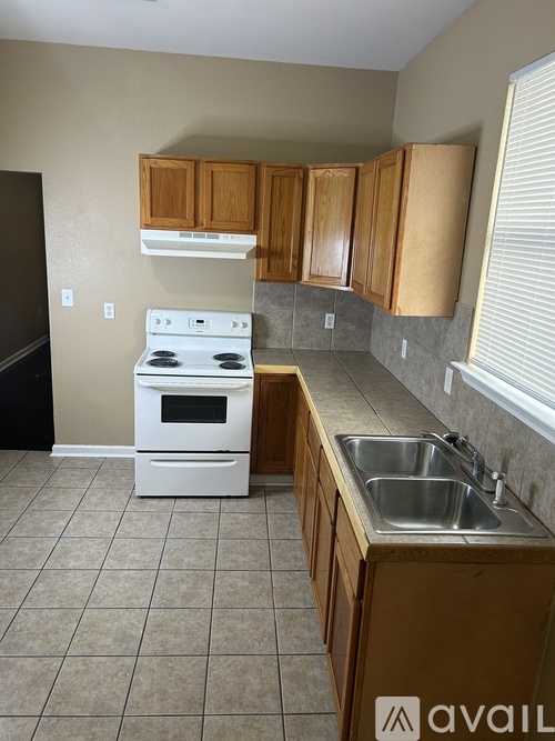 A kitchen with a white stove top oven and a white sink.