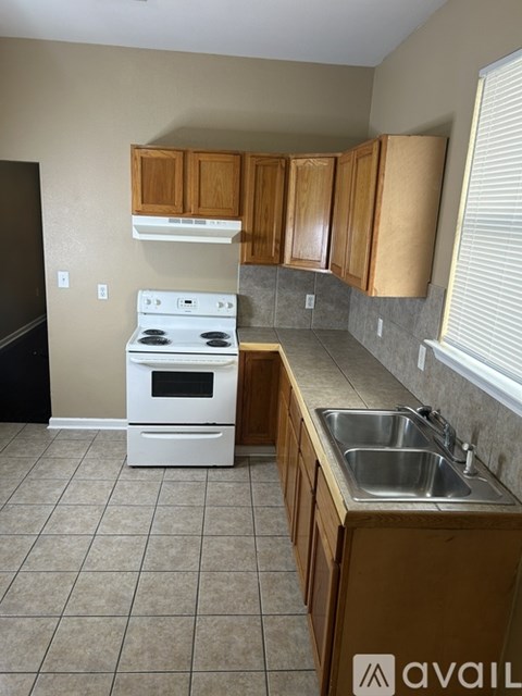 A kitchen with a white stove top oven and a white sink.