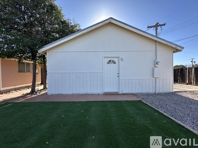 A small white building with a green lawn in front.