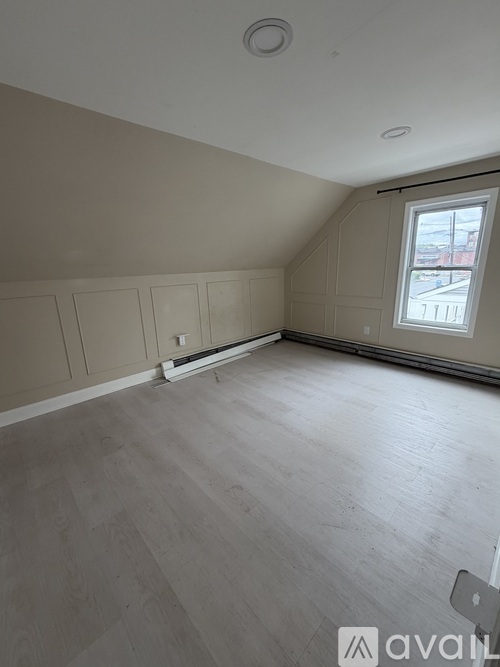 A room with a window and wooden flooring.