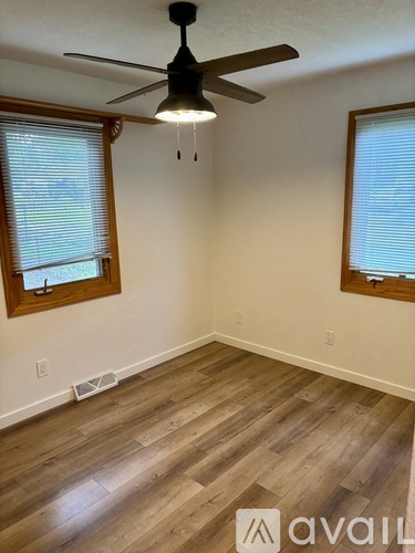 A room with a ceiling fan and wooden flooring.