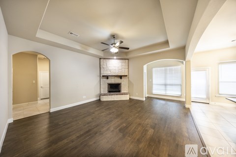 A spacious living room with wood flooring and a fireplace.
