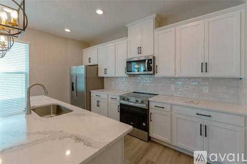 A kitchen with white cabinets and a marble countertop.