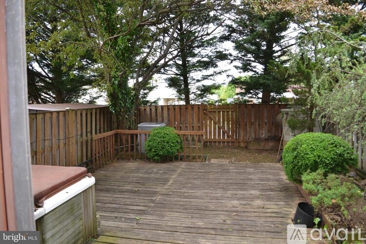 A backyard with a wooden deck and a hot tub.