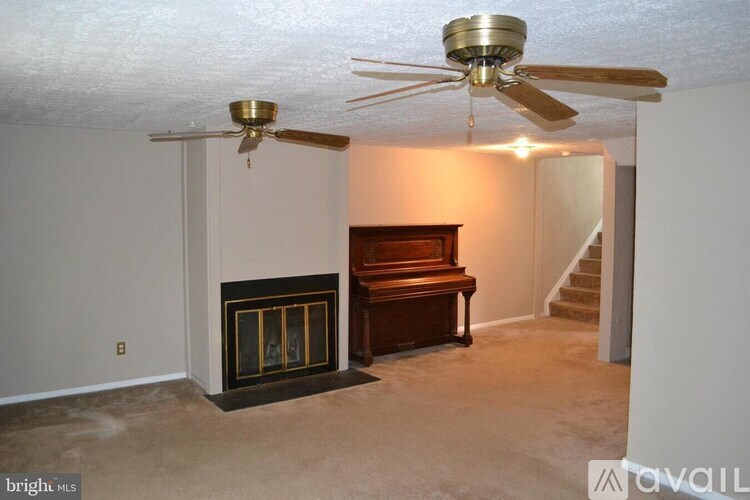 A living room with a fireplace, a piano, and a ceiling fan.
