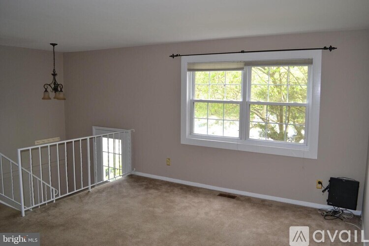A room with a window, a chandelier, and a white railing.