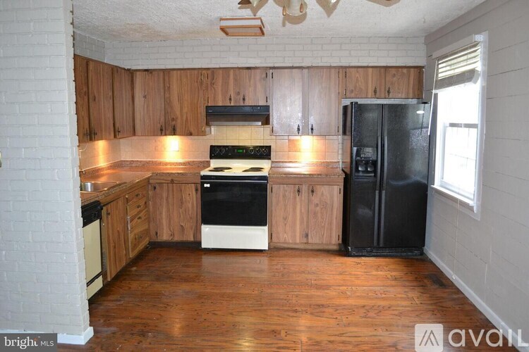 A kitchen with wooden cabinets and a black fridge.