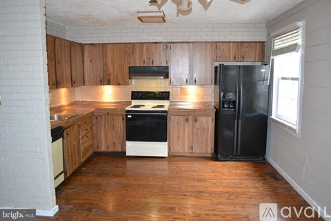 A kitchen with wooden cabinets and a black fridge.